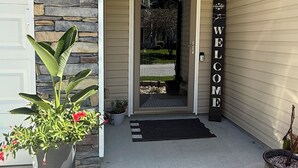 A house entrance with a stone wall, a welcome sign, and a potted plant. - One story 4 bedroom updated ranch in the middle of it all. (Simpsonville)