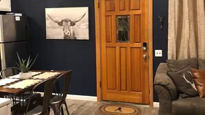 Ein Essbereich mit Holztisch und -stühlen, einem Kühlschrank, einer Topfpflanze und einem an der Wand befestigten Hirschschädel.