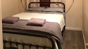 Ein kleines, gemütliches Schlafzimmer mit zwei Betten, einer Holzbalkendecke und einem Fenster mit Vorhängen.