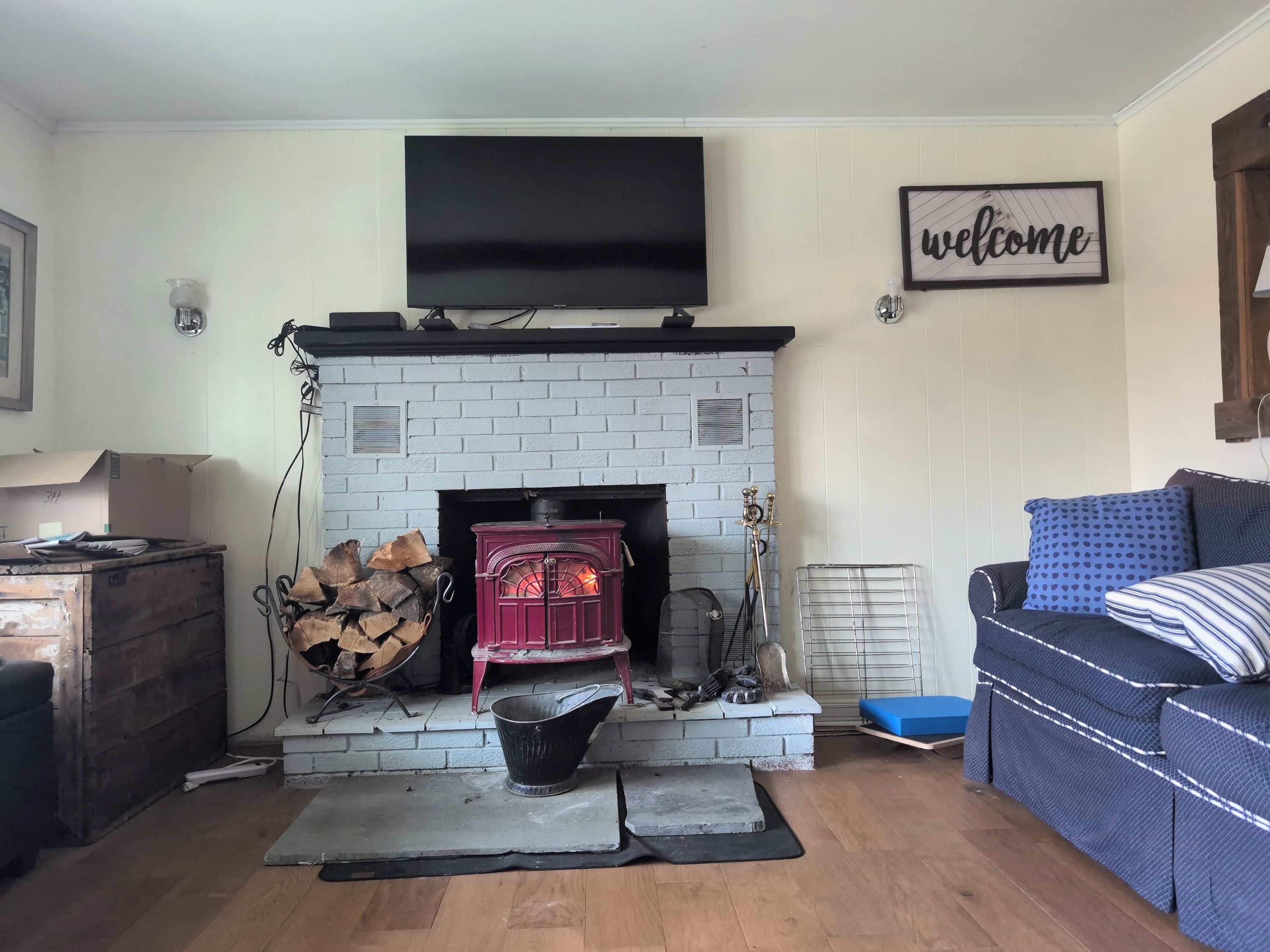 A living room with a fireplace, a sofa, and a television mounted on the wall.