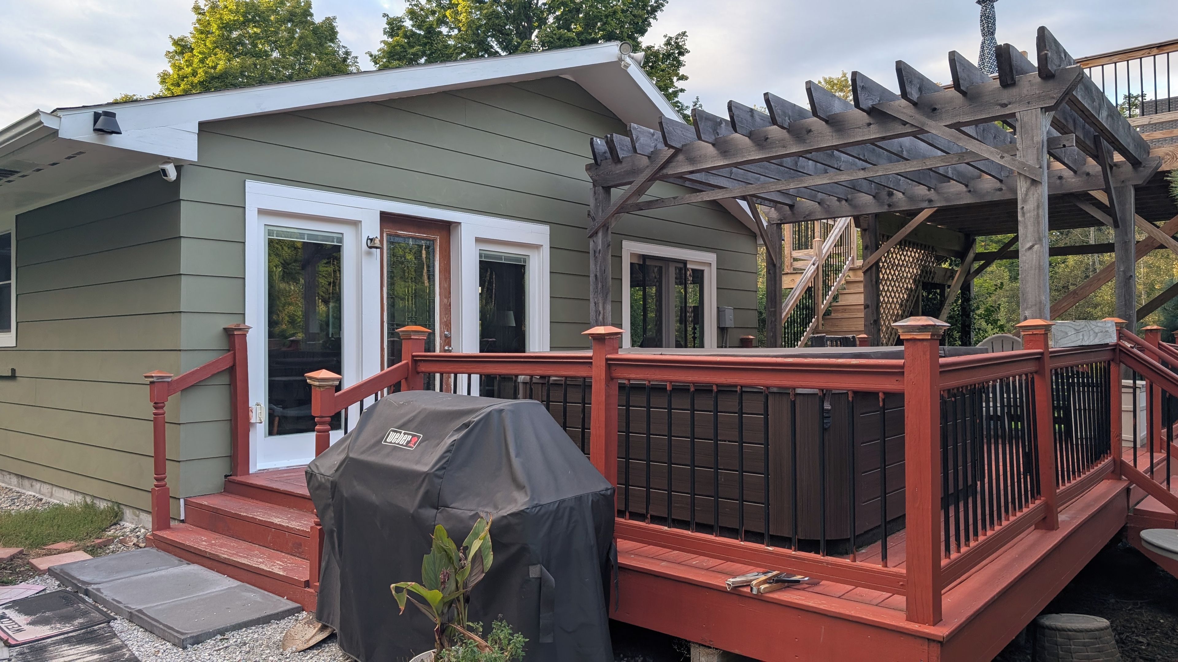 Une maison dotée d’une terrasse couverte, d’un barbecue et d’une pergola en bois.