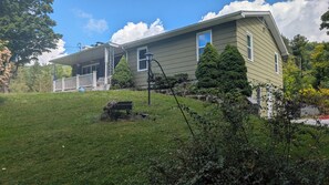 A two-story house with a front porch, a lawn, and a small garden area. - large ski ranch hot tub close to killington pets ok (Mendon)
