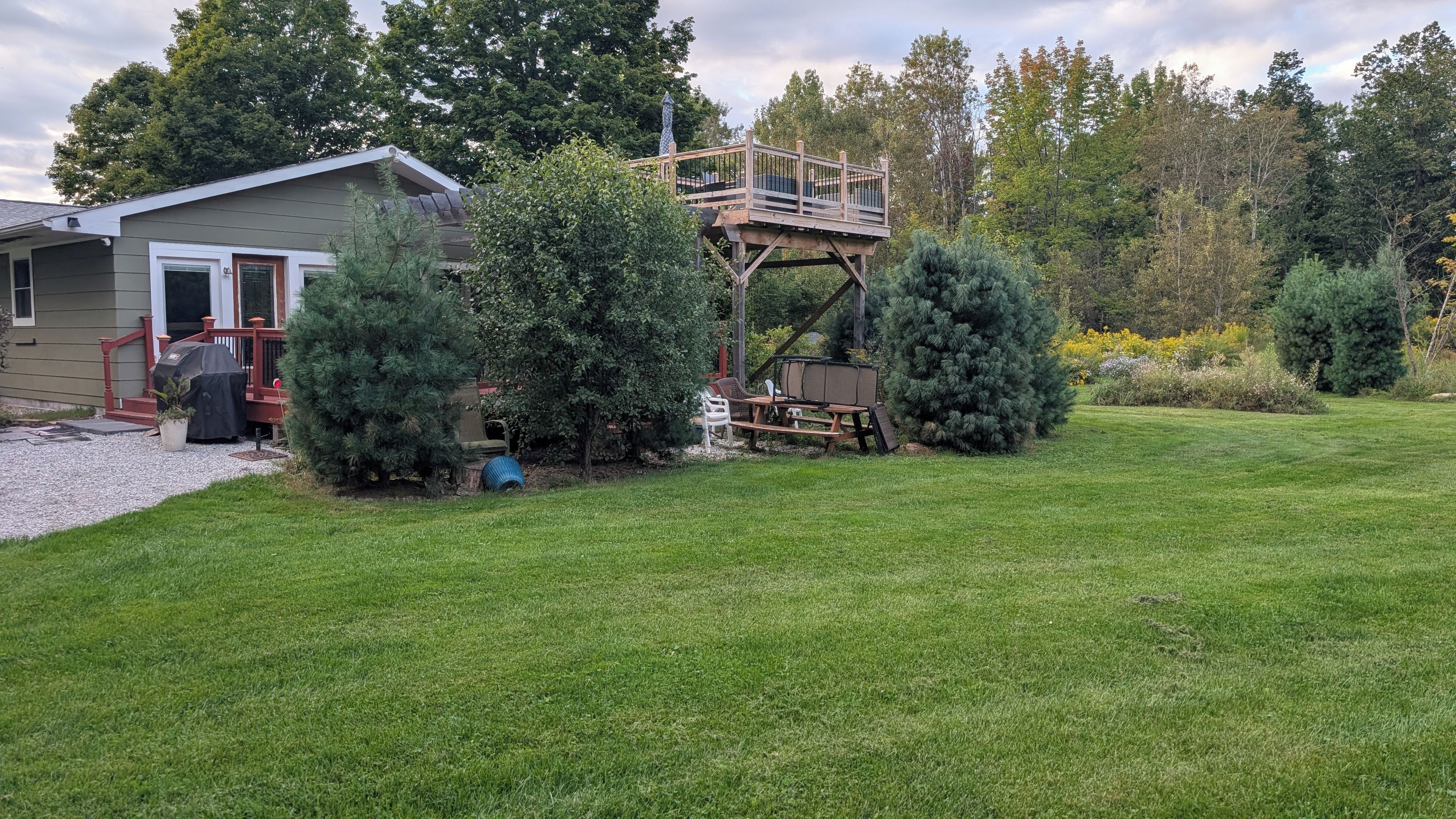 A residential property with a covered barbecue area, a wooden deck, and a well-maintained lawn.