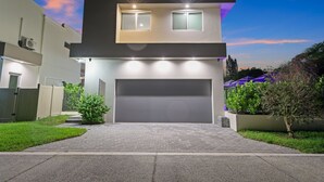 Ein modernes, zweistöckiges Haus mit Garage, Auffahrt und gepflegtem Rasen.