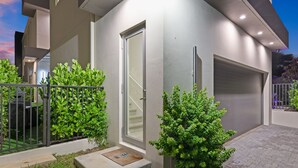 Ein modernes, zweistöckiges Haus mit Garage, kleiner Veranda und gepflegtem Rasen.