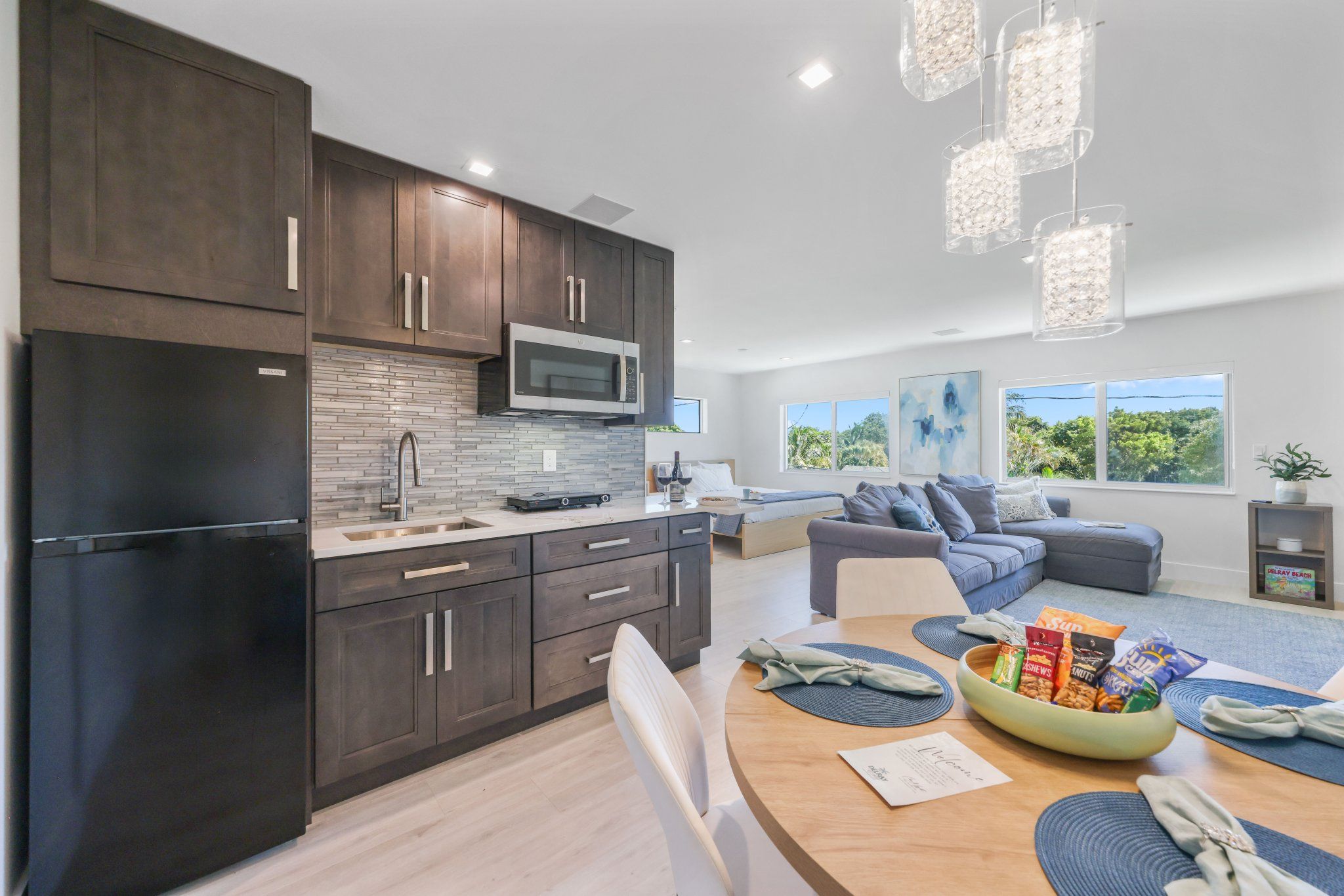 A modern kitchen with dark cabinets, a stainless steel sink, and a microwave.