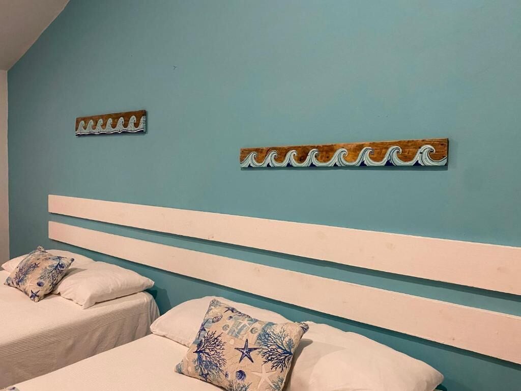 A bedroom with two beds, each with a white headboard and decorative pillows.