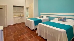 Une chambre d’hôtel avec deux lits simples, une kitchenette et une salle de bain.