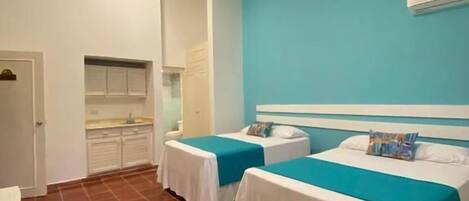 Une chambre d’hôtel avec deux lits simples, une kitchenette et une salle de bain.