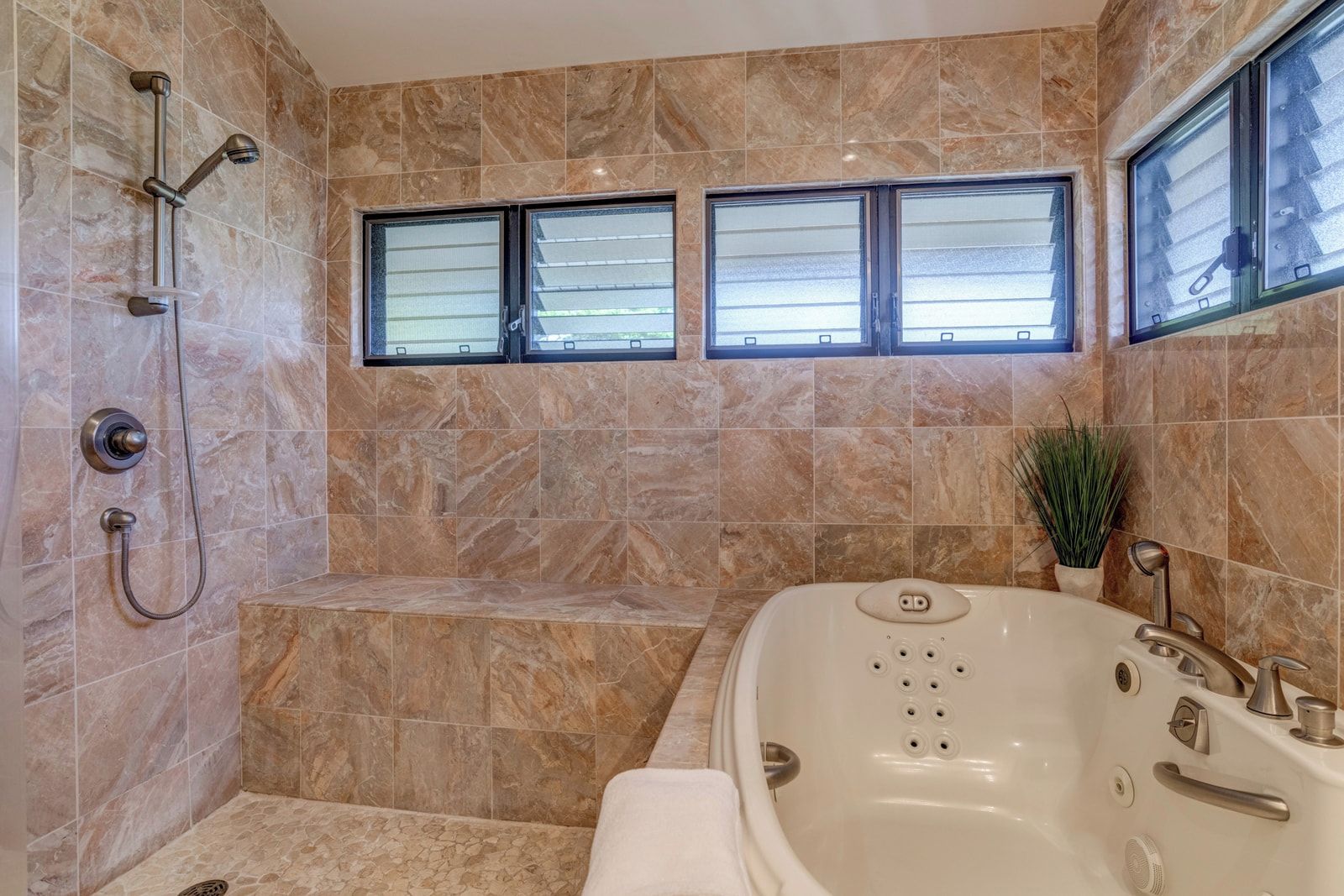 Ein Badezimmer mit einer Badewanne, einer Dusche und zwei Fenstern.