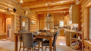 A wooden cabin interior with a dining area, kitchen, and a large window. - 'Riverfront Ranch' Craig, Montana (Cascade)
