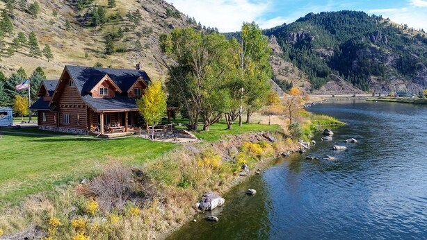 A log cabin with a porch, situated by a river with a mountain backdrop. - 'Riverfront Ranch' Craig, Montana (Cascade)
