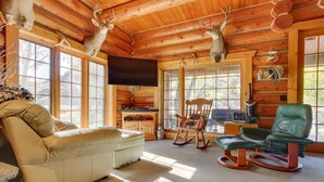 A log cabin interior with a sofa, rocking chair, and a television. - 'Riverfront Ranch' Craig, Montana (Cascade)