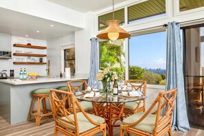 A dining area with wicker chairs, a glass table, and a view of the outdoors. - Kapalua Ridge | Ocean View 5 BR, Sleeps 14 | Car Incl. w/ 6+ Nights | KRV ML-2165 by KBM (Lahaina)