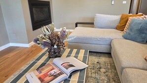 A living room with a sofa, a coffee table with a magazine, a decorative vase, and a patterned rug. - Luxury accommodation Jindabyne. Weekly and monthly discounts (Jindabyne)