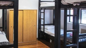 A dormitory room with bunk beds, wooden flooring, a ceiling fan, and a window. - Hostel Pituco (Mendoza)