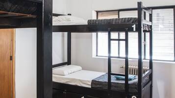 Une chambre avec un lit superposé, un ventilateur de plafond, un appareil de climatisation et une fenêtre avec des stores.