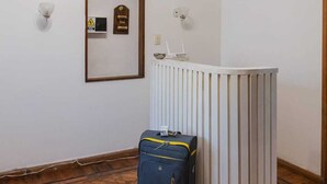 A hotel room with a wooden ceiling fan, a radiator, a framed certificate on the wall, a hat on the wall, and a suitcase on the floor. - Hostel Pituco (Mendoza)