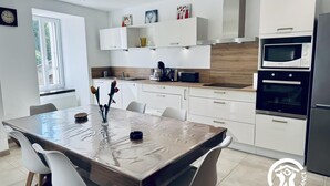 A modern kitchen with white cabinets, a wooden countertop, and stainless steel appliances. - L'Ensoleillée le petit (TRASSANEL)