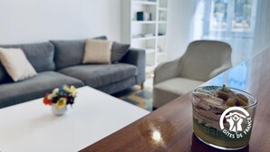 A modern living room with a grey sofa, a beige armchair, and a coffee table with a glass of dessert. - L'Ensoleillée le petit (TRASSANEL)