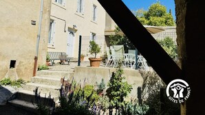 A courtyard with a building, steps, and outdoor furniture. - L'Ensoleillée le petit (TRASSANEL)