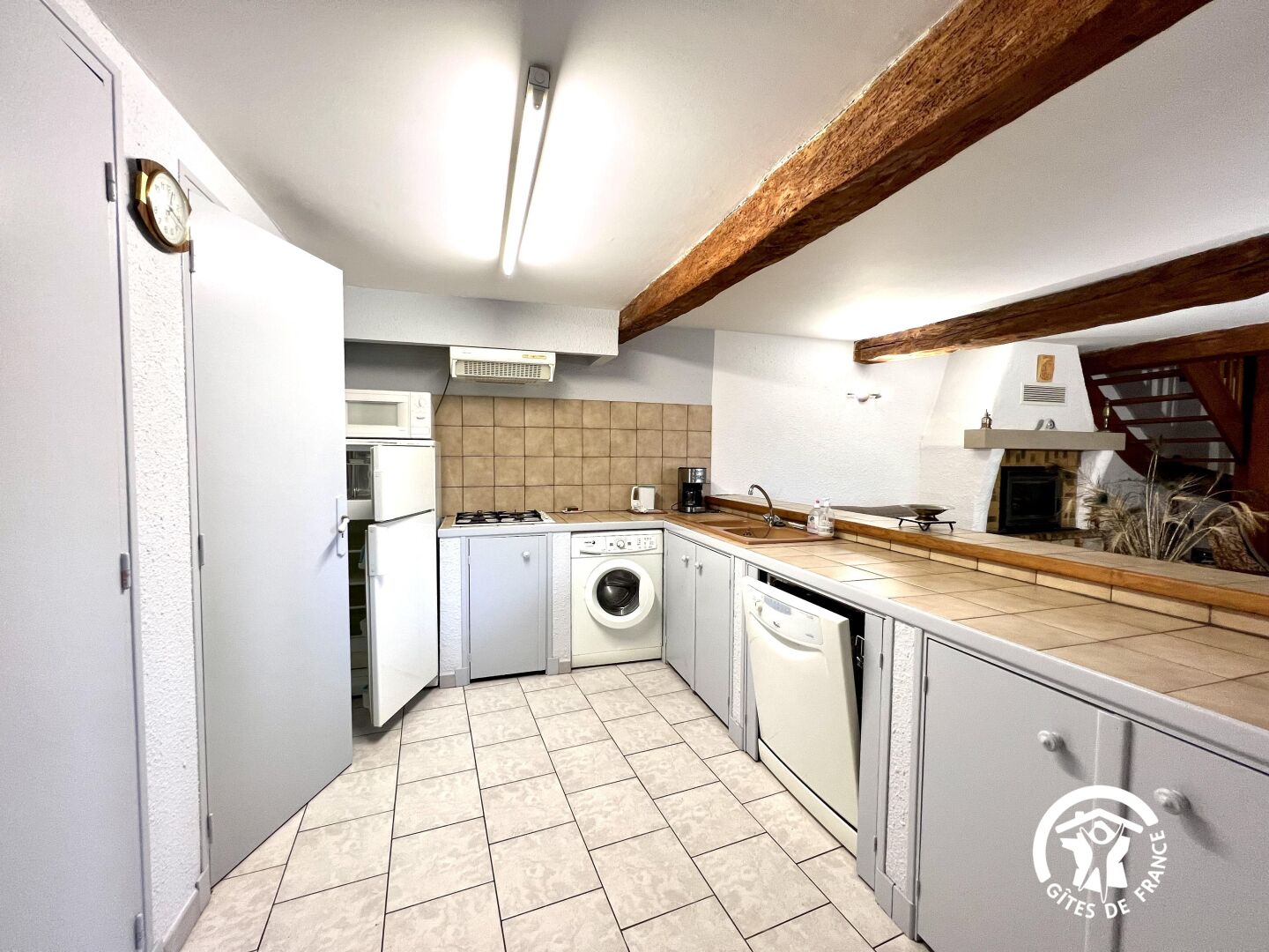 A compact kitchen with a washing machine, microwave, and gas stove.