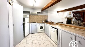 A compact kitchen with a washing machine, microwave, and gas stove. - La Migance - ALZONNE (ALZONNE)