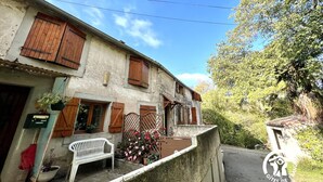 A rustic building with wooden shutters, a bench, and potted plants. - La Migance - ALZONNE (ALZONNE)