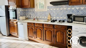 Una cocina con armarios de madera, lavavajillas, microondas y cafetera.