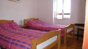 A bedroom with two wooden beds, a nightstand, and a chair. - La Loggia - ROQUEFORT DES CORBIERES (ROQUEFORT DES CORBIERES)