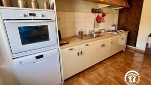 A kitchen with a built-in oven, a dishwasher, and a stove. There are wooden cabinets and a tiled backsplash. - La Grange - CAMURAC - Gîte (CAMURAC)