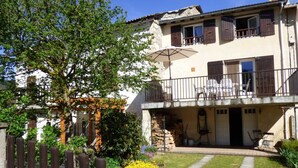 A two-story house with a balcony, a garden with a wooden fence, and outdoor furniture. - La Grange - CAMURAC - Gîte (CAMURAC)