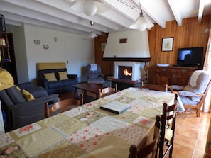 A cozy living room with a fireplace, a television, and a dining area with a quilt-covered table.