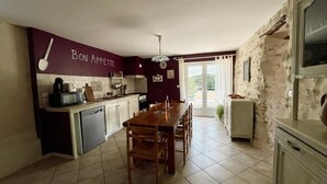 Una cocina con una mesa de comedor, sillas, microondas y lavamanos.