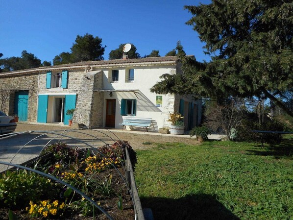 A two-story stone house with blue shutters, a small garden, and a bench outside. - Le Camberaud - MAILHAC (MAILHAC)