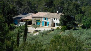 Una casa de piedra con tejado de baldosas, rodeada de un bosque frondoso.