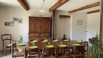 Une salle à manger avec une table en bois dressée pour six personnes, entourée de chaises en bois dont les assises sont en osier tressé.
