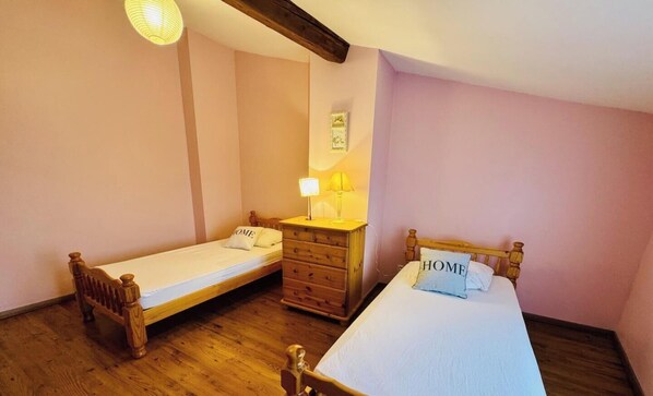 A bedroom with two wooden beds, a wooden dresser, and a lamp. - Coté colline - ANTUGNAC (ANTUGNAC)