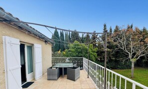 A balcony with a table and chairs, a white railing, and a view of trees and a lawn. - Coté colline - ANTUGNAC (ANTUGNAC)