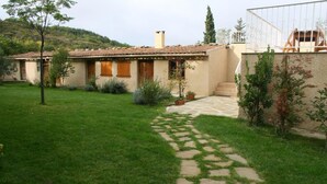 Une maison avec un chemin de pierre menant à l’entrée, entourée d’une pelouse bien entretenue et de diverses plantes.