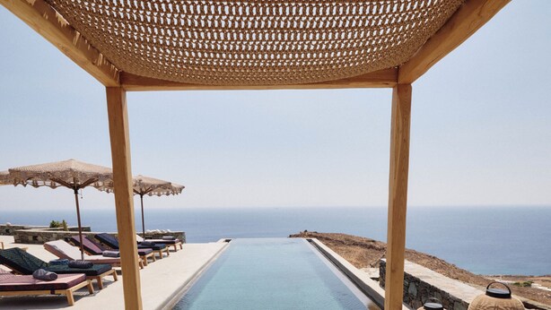 A poolside lounge with a pergola, lounge chairs, and a view of the sea. - Heavenly views from Villa Nites with stunning infinity pool (Megas Gialos)