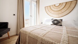 A bedroom with a large bed, a view of the outdoors, and a chair. - Heavenly views from Villa Nites with stunning infinity pool (Megas Gialos)