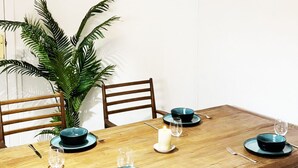 A dining table with chairs, a hanging light fixture, a potted plant, and a wall with colorful artwork. - 2BR Cathedral & Giralda Views, Rooftop Terrace! (Sevilla)