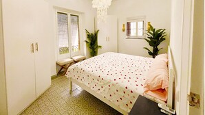 A bedroom with a bed, a window with blinds, a chandelier, and a potted plant. - 2BR Cathedral & Giralda Views, Rooftop Terrace! (Sevilla)