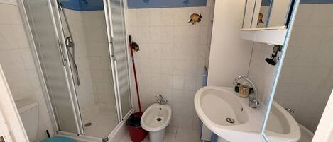 A bathroom with a glass-enclosed shower, a toilet, a bidet, and a sink.