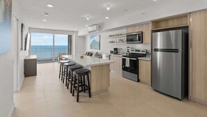Una cocina moderna con una isla central, electrodomésticos de acero inoxidable y vistas al exterior.