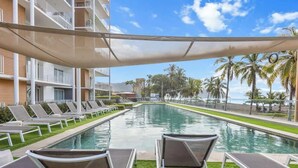 Un área junto a la piscina con sillones de descanso y vista al océano.