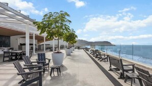 Una terraza en la azotea con mobiliario exterior, una planta grande en maceta y vistas al océano.