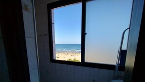 Ein Badezimmer mit Blick auf einen Strand durch ein Fenster.