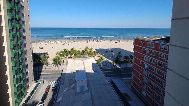 Blick auf einen Strand vom Hochhaus aus, mit blauem, wolkenlosem Himmel.